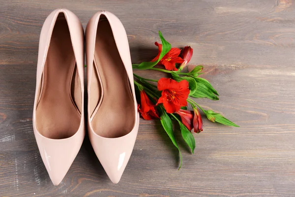 Kvinnliga skor med blommor på trä bakgrund — Stockfoto
