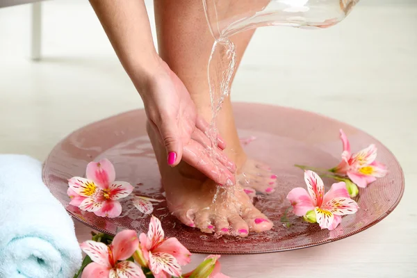 Vrouw wassen mooie benen in kom, op lichte achtergrond. Spa procedure concept — Stockfoto