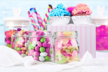 Cam Kavanoz ve cupcakes renk ahşap arka plan üzerinde çok renkli şekerler