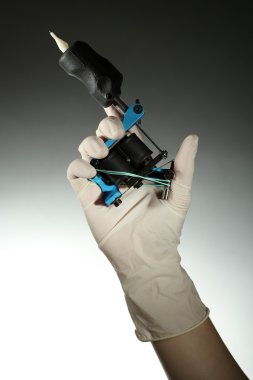 Dövme makinesi, renkli arka plan üzerinde tutarak dövme sanatçısı