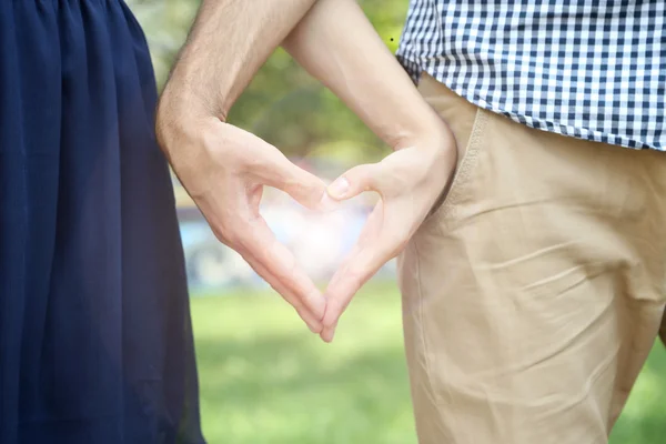 Verliefde paar hand in hand in de vorm van hart, buitenshuis — Stockfoto