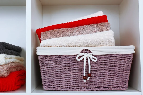 Asciugamani colorati con cesto di vimini su scaffale di sfondo rack — Foto Stock