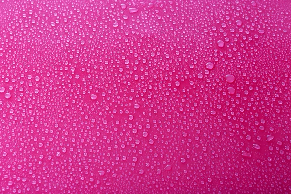 Water druppels op glas op roze achtergrond — Stockfoto