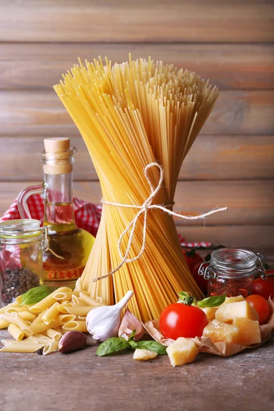 Pasta with cherry tomatoes and other ingredients on wooden background — Stock Photo, Image