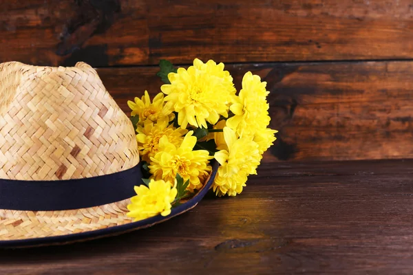 Chapeau avec des fleurs sur fond en bois — Photo