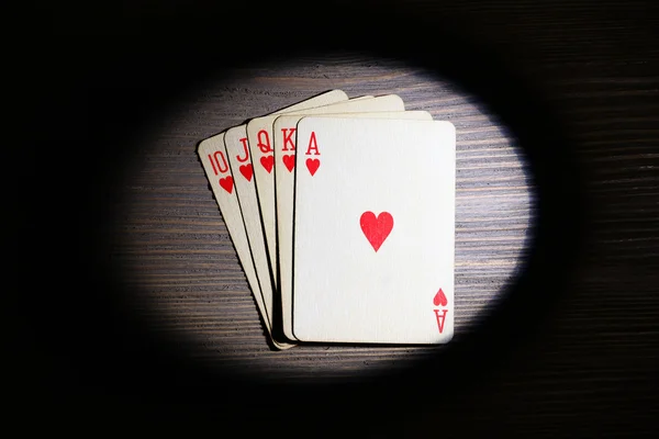 Speelkaarten in licht op houten tafel, bovenaanzicht — Stockfoto