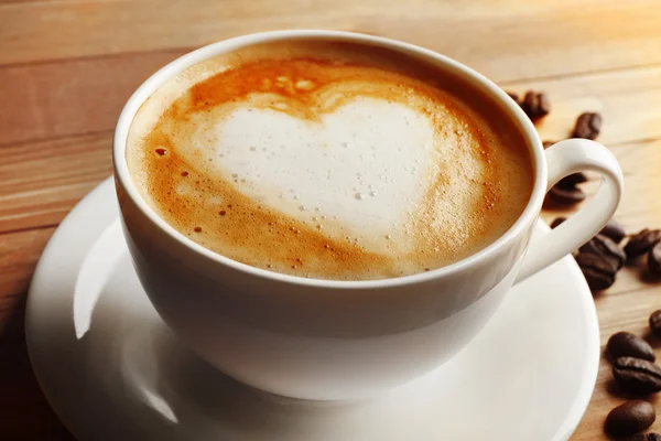 Kopp kaffe latte art med korn på träbord, närbild — Stockfoto