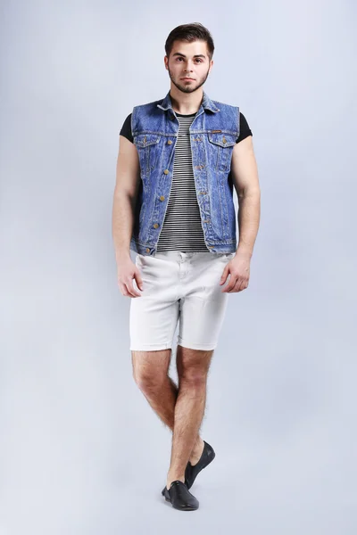 Man in white shorts and jeans vest on gray background — Stock Photo, Image