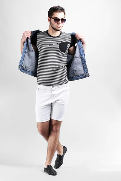 Man in white shorts and jeans vest on gray background — Stock Photo, Image