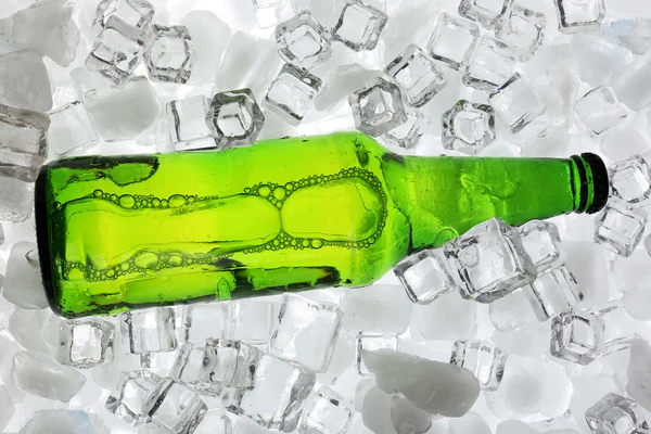 Botella de vidrio de cerveza sobre fondo de cubos de hielo — Foto de Stock