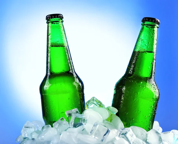 Botellas de vidrio de cerveza en cubos de hielo sobre fondo de color —  Fotos de Stock