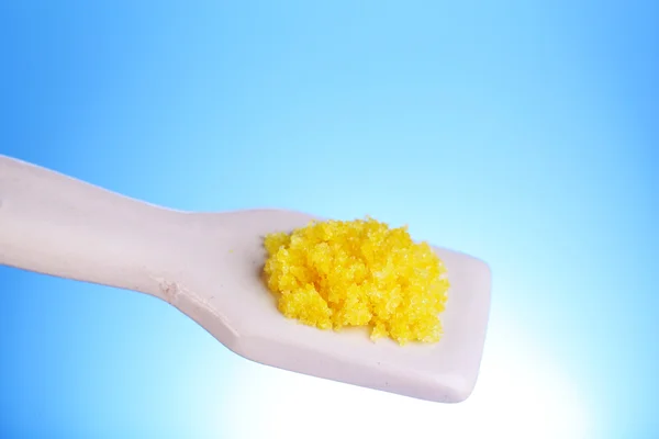 Laboratory spatula with granules on blue background — Stock Photo, Image