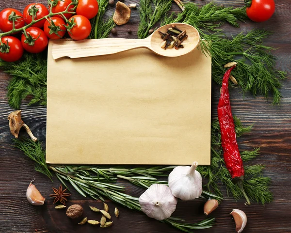 Open recipe book with fresh herbs, tomatoes and spices on wooden background