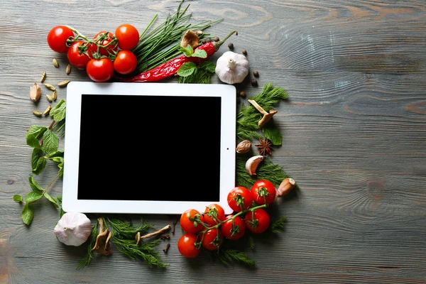 Tableta digital con hierbas frescas, tomates y especias sobre fondo de madera — Foto de Stock