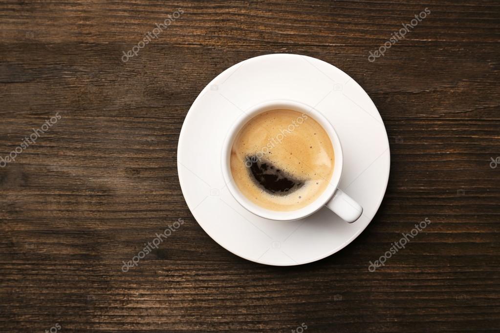 Cup of coffee on wooden table, top view