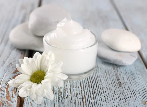 Crema cosmetica con fiori e pietre termali su sfondo di legno — Foto Stock