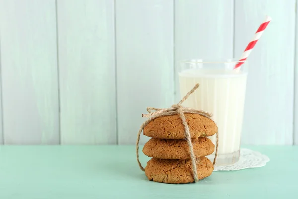 Chutné cookies a sklenici mléka na barevné dřevěné pozadí — Stock fotografie