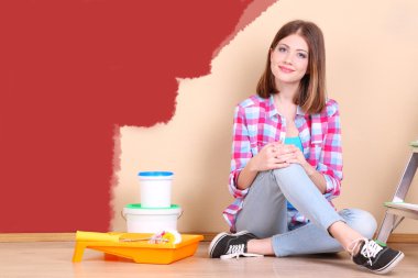 Güzel kız boyama duvar için ekipman ile yerde yatarken