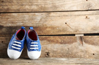 ahşap arka plan üzerinde renkli yürümeye başlayan çocuk ayakkabı