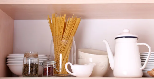 Kitchen utensils and tableware on wooden shelf — Stock Photo, Image