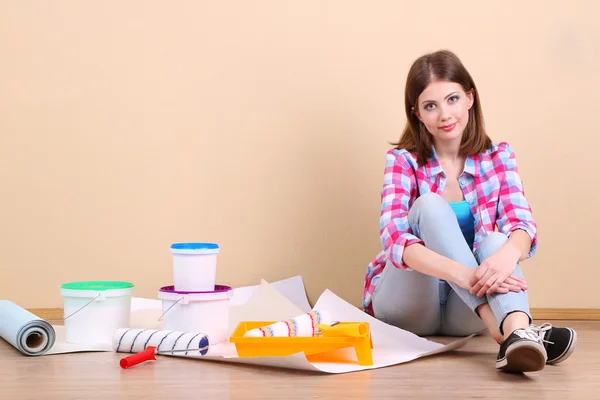 Schönes Mädchen auf dem Boden sitzend mit Geräten zum Malen der Wand — Stockfoto