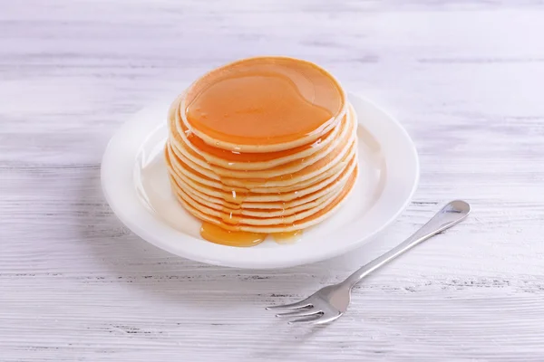 Вкусные блинчики с медом на тарелке на столе крупным планом — стоковое фото
