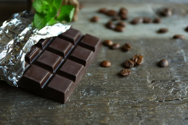 Шоколад с мятой и кофейными зёрнами на деревянном фоне — стоковое фото