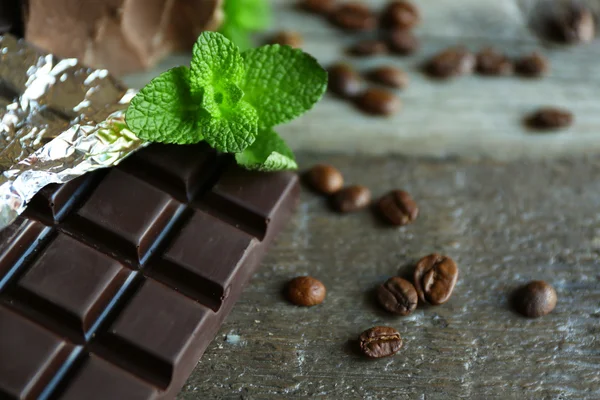 Шоколад с мятой и кофейными зёрнами на деревянном фоне — стоковое фото