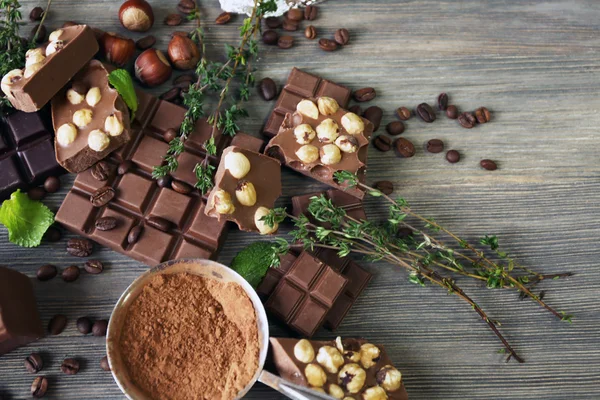 Sada Čokoláda s oříšky, bylinky a kávová zrna na dřevěný stůl, detail — Stock fotografie