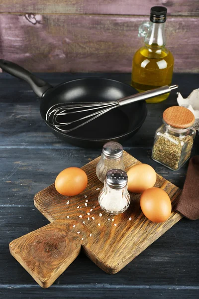 Stilleven met eieren en pan op houten achtergrond — Stockfoto