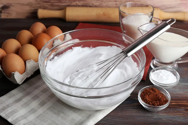 Brancos de ovo chicoteado para creme e outros ingredientes em mesa de madeira, close-up — Fotografia de Stock