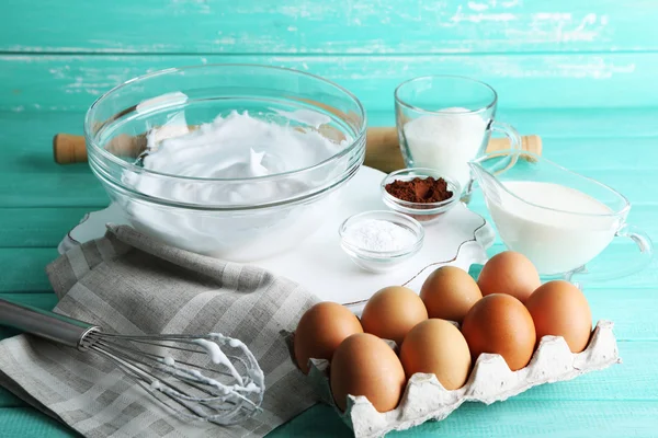 Geschlagenes Eiweiß für Sahne auf farbigem Holzhintergrund — Stockfoto