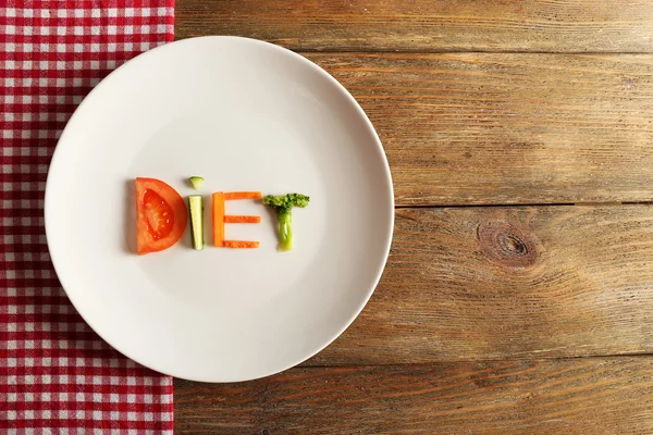 Słowo dieta wykonane w plasterkach warzywa w białe płytki z serwetka na drewniane tła — Zdjęcie stockowe
