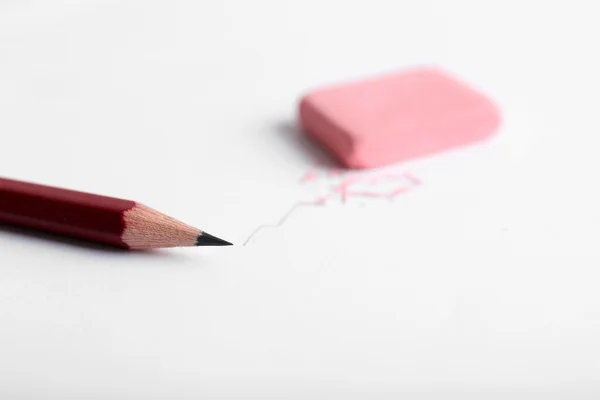 Eraser och penna på papper bakgrund — Stockfoto