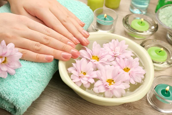Kvinnliga händer och skål med spa vatten med blommor, närbild — Stockfoto