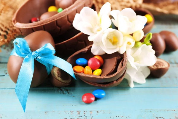 Schokoladen-Ostereier mit Blumen auf Holztisch, Nahaufnahme — Stockfoto