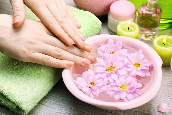 Mãos femininas com tigela de água de spa de aroma em mesa de madeira, close-up — Fotografia de Stock