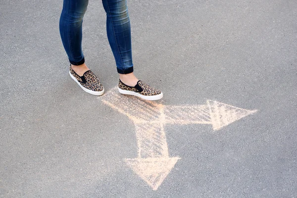 Női láb és a rajz nyilak a járdán háttér — Stock Fotó