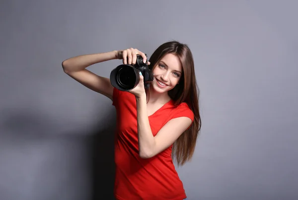 Joven fotógrafa tomando fotos sobre fondo gris — Foto de Stock