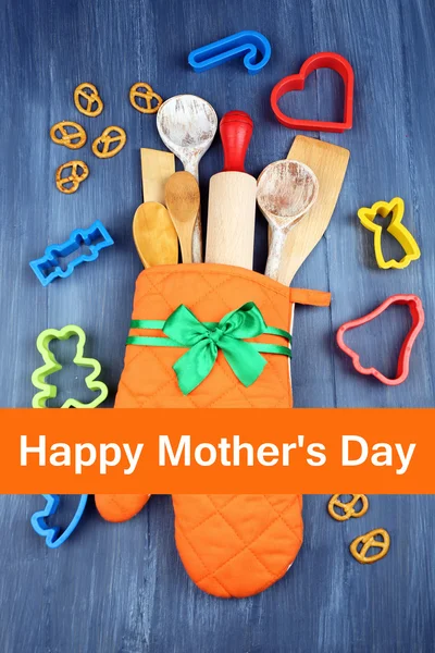 Verschiedene Küchenutensilien in Topflappen auf Holzgrund, Muttertagsgrußkarte — Stockfoto