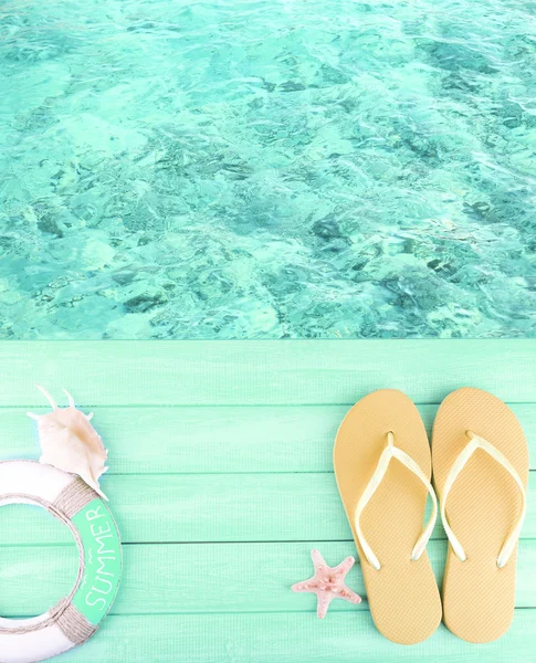 Chanclas femeninas en plataforma de madera al lado del mar — Foto de Stock