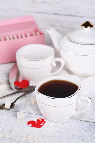 Tazza da tè a forma di cuore tag, scatola e teiera su sfondo di legno — Foto Stock