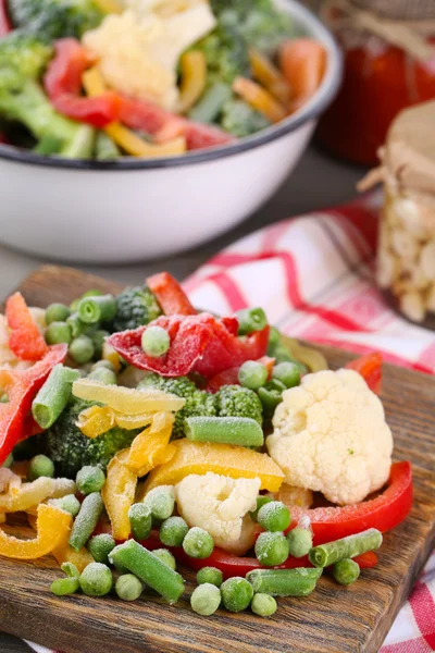 Verduras congeladas sobre tabla de cortar, sobre servilleta, sobre fondo de mesa de madera — Foto de Stock