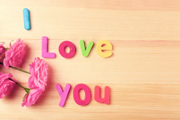 Mooie rozen met woord Love op houten achtergrond — Stockfoto