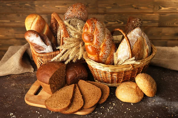Pâine diferită cu urechi în coș pe fundal din lemn — Fotografie, imagine de stoc