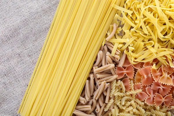 Verschiedene Arten von Pasta auf Sacktuch Hintergrund — Stockfoto