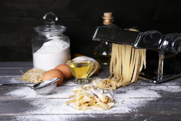 Metall pasta maker maskin och ingredienser för pasta på trä bakgrund — Stockfoto