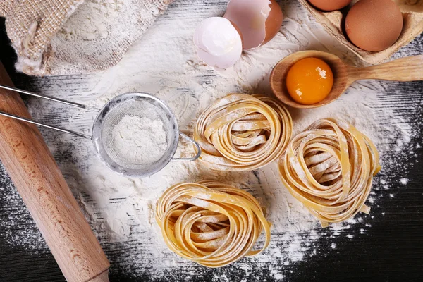 Pasta mentah buatan sendiri dan bahan-bahan untuk pasta pada latar belakang kayu — Stok Foto