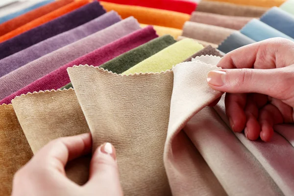 Женщина выбирает кусочки цветной ткани на столе крупным планом — стоковое фото