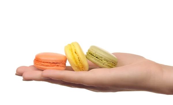 Läckra färgglada macaroons i kvinnlig hand isolerad på vit — Stockfoto